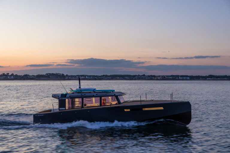 Un Nomad 40 avance à vitesse de croisière au coucher du soleil, son grand cockpit chaleureusement éclairé