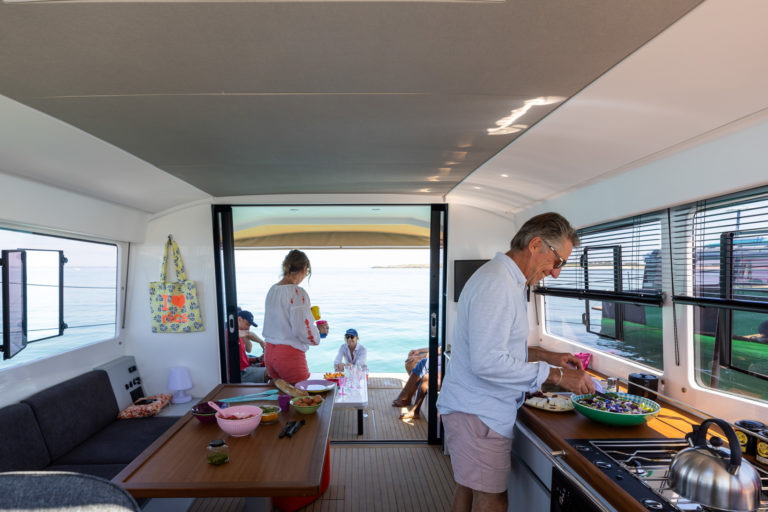 Préparation du repas par l'équipage dans la cuisine, avec beaucoup de luminosité et une vue panoramique grâce aux larges fenêtres